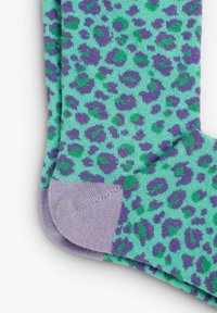 Calcetines de leopardo en verde menta con manchas moradas y verdes. Tejido texturizado con una sensación suave y elástica y una sección de los dedos en morado que contrasta.