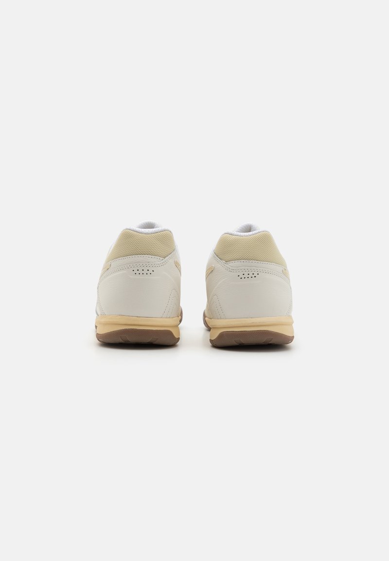 Zapatillas deportivas blancas con upper de cuero suave, detalles de malla, cuello acolchado y suela de goma texturizada.