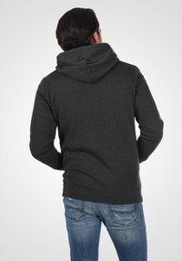 Charcoal gray hooded sweatshirt with a relaxed fit, ribbed cuffs and hem, and a kangaroo pocket. Worn with light blue distressed jeans.