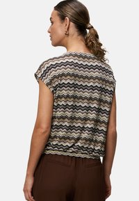 T-shirt med korte ærmer i et zigzag-mønster med farverne brun, grøn, creme og sort. Letvægtsmateriale med en afslappet pasform og rund halsudskæring.