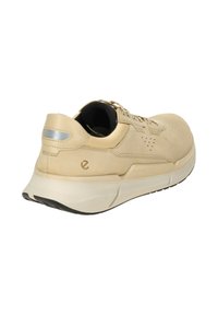 Beige athletic shoe with a smooth leather upper, rounded shape, black textured lining, and a white midsole featuring a black outsole.