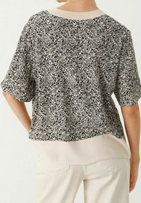 Bloemig kortmouwtop met een gestructureerd zwart-wit patroon, met een effen lichte achterkant en een geribde halsband.