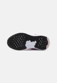 Suela de zapatilla Nike con una banda de rodadura de goma negra, que presenta una mezcla de patrones hexagonales y ovalados, y una mediasuela blanca lisa.