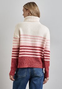 Pullover in maglia accogliente con colletto alto, righe color crema e rosa che sfumano in un orlo rosso scuro, con polsini e fondo ribattuti.