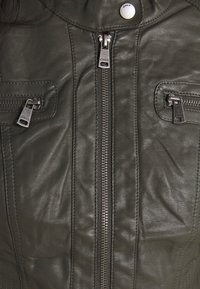 Ciemnozielona skórzana kurtka z centralnym zamkiem błyskawicznym, dwoma zamykanymi kieszeniami oraz przeszyciami po bokach. Srebrne elementy ozdobne.