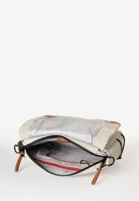 Lichtgrijze schoudertas met een getextureerde binnenkant met een rasterpatroon, een rood ritsvak en bruine lederen accenten. Ritssluiting.