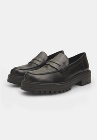 Melnās ādas loafers ir ar šūšanas detaļu un zemu, biezu gumijas zoli ar teksturētu rakstu. Gluda apdare bez papildus akcentiem.
