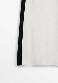 Hvidt stof med en glat tekstur, der har en fed sort lodret stribe langs den ene side. Simpelt, moderne design.