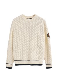 Cremfarbener Kabelstrickpullover mit ribbeltem Rundhalsausschnitt, navygestreiftem Saum und einem Aufnäher am linken Ärmel mit dekorativem Design.