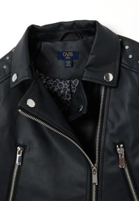 Veste de moto en simili cuir noir avec quincaillerie argentée, doublure à imprimé léopard et accents en clous sur les épaules. Poches zippées.