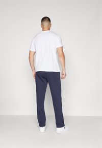 White short-sleeve T-shirt paired with navy sweatpants. The sweatpants have a relaxed fit and are made of soft fabric.