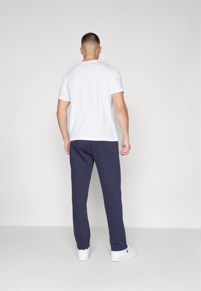 T-shirt blanche à manches courtes associée à un pantalon de survêtement marine. Le pantalon de survêtement a une coupe décontractée et est fabriqué en tissu doux.