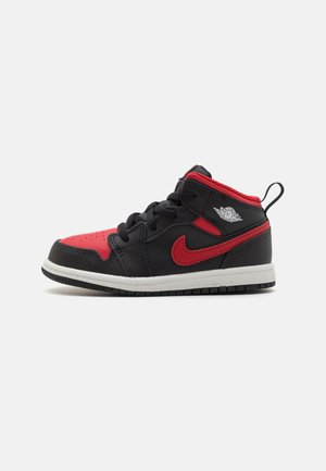 Sort og rød mid-top sneakers i læder og tekstil, med perforeret tå, snørebånd og gummisål.
