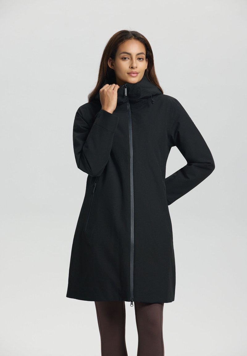 Manteau imperméable noir au design ajusté, col haut, capuche réglable et fermeture éclair à l'avant. Dispose de poches latérales et de manches longues.
