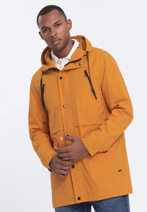 Geel waterproof jack met capuchon, voorzien van een voorste drukknoopsluiting, verstelbare touwen en twee voorzakken. Soepele textuur, casual ontwerp.