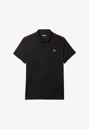 Musta polo-paita, joka on valmistettu sileästä kankaasta. Siinä on kaulus, lyhyet hihat ja punaisia yksityiskohtia olkapäissä. Rintapaidassa on vihreä logo.