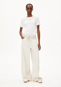 Top corto de punto blanco de manga corta con una textura sutil, combinado con pantalones anchos de color blanco roto, holgados y con cintura con cordón.