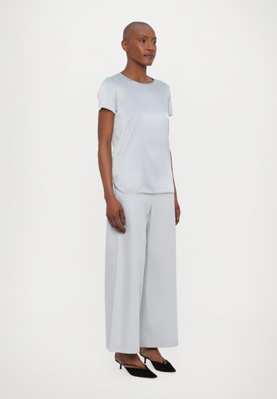 Top azul claro de manga curta com gola redonda, combinado com calças largas azul claro e sapatos de salto pretos. Tecido suave e corte descontraído.