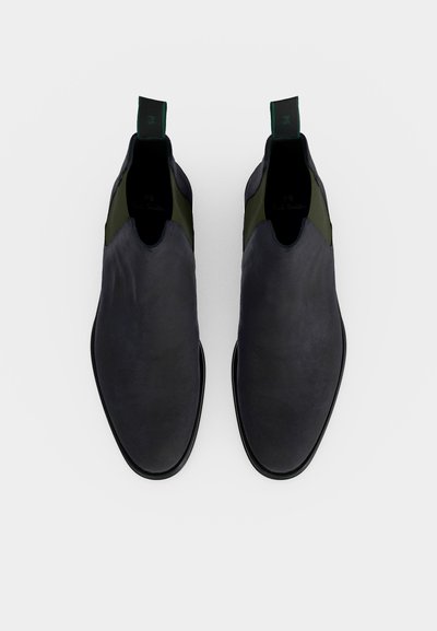 Μαύρα δερμάτινα μποτάκια Chelsea slip-on με πράσινες ελαστικές πλαϊνές επενδύσεις και πράσινες θηλιές, σε άποψη από πάνω πάνω σε λευκό φόντο.