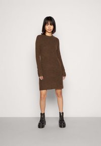 Brown knitted dress with long sleeves and a round neckline. Features a slightly fitted silhouette and a hem that falls above the knee.
