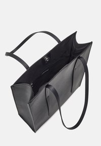 Svart rektangulär läder tote-väska med dubbla handtag, öppen topp, innervägg med dragkedja och magnetknäppning på vit bakgrund.