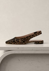 Leopardmønstret slingback flath sko med spiss tupp og lav blokkhæl på en lys marmoroverflate.