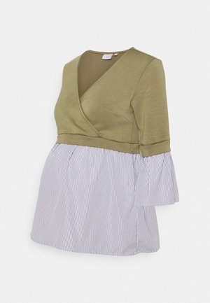 Oliwkowo-zielona bluzka w stylu wiązanym z rękawami do połowy przedramienia połączona z białym i granatowym, pionowo prążkowanym rozkloszowanym dołem.