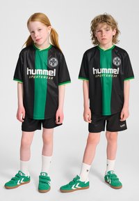 Zwart-groene gestreepte sportshirts met bijpassende shorts. Groene sneakers met klittenbandsluitingen en witte sokken, beide met logo-accenten.