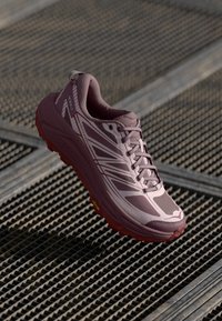 Hellblaues Laufschuh mit strukturiertem Obermaterial, atmungsaktivem Mesh, unterstützendem Schnürsystem und einer roten Gummisohle. Verfügt über diagonale weiße Streifen.