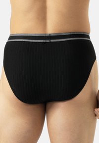 Schwarze gerippte Slips mit einem breiten elastischen Bund, der graue Akzente aufweist. Der Stoff wirkt weich, mit enganliegender Passform und minimaler sichtbarer Naht.