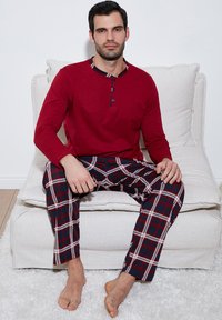Rød langærmet pyjamasbluse med etternede krave, parret med marineblå, rød og hvid ternede bukser. Blødt stof, afslappet pasform og detaljeret syning.