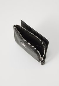 Μαύρο δερμάτινο πορτοφόλι με φερμουάρ, διαθέτοντας δύο διαμερίσματα και ασημένια εξαρτήματα. Υφή στην εξωτερική επιφάνεια και λείο εσωτερικό ύφασμα.