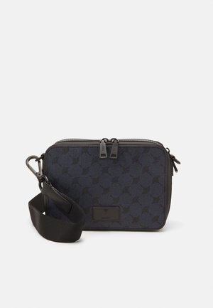 Mørkeblå crossover-bag med en teksturert overflate, preget av et geometrisk mønster, to glidelåslukkinger og en avtakbar stropp.