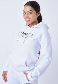 Witte hoodie met een voorzak, voorzien van een meerkleurig gedrukt logo. Zachte stof, relaxed fit en ribgebreide manchetten.