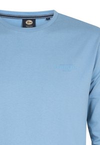 Ljusblå crewneck sweatshirt med ribbad struktur, en varumärkeslogotyp i matchande färg på bröstet och en randig krage.