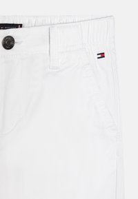 Białe bawełniane chinosy o teksturowanym wykończeniu, z zapięciem na guzik, elastycznym pasem i małym logo na kieszeni.