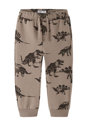 Pantalon marron pour tout-petit avec taille élastique, cordon de serrage et imprimés de dinosaures noirs, incluant des motifs de T-Rex et stégosaure.