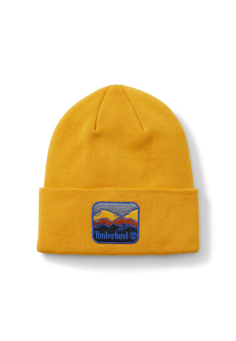 Žlutá pletená čepice s ohrnutím, s barevným vyšitým logem zobrazujícím hory a názvem značky "Timberland".
