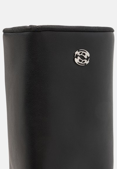 Botă din piele neagră cu un design elegant. Partea de sus are o manșetă pliată și include un accent cu un logo argintiu pe lateral. Textură netedă, cusături minime.