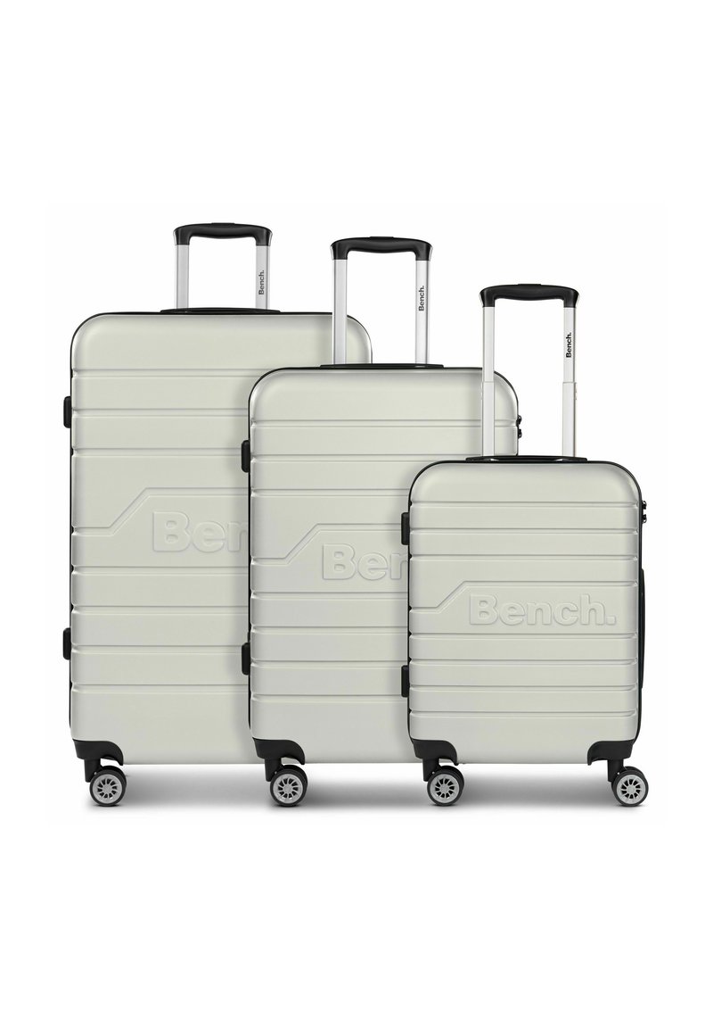 Set di tre valigie rigide di color grigio chiaro con una finitura testurizzata, dotate di maniglie estensibili e quattro ruote per la mobilità.