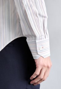 Camisa de botones con rayas verticales multicolores. Hecha de una tela ligera, con un cuello puntiagudo, puños abotonados y un dobladillo ligeramente curvado.
