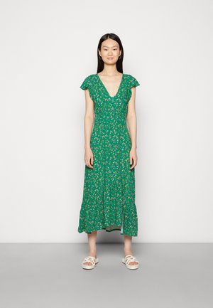 Vestido floral verde com decote em V, mangas curtas com babados e saia em camadas. O tecido possui uma textura leve e está adornado com pequenas flores.