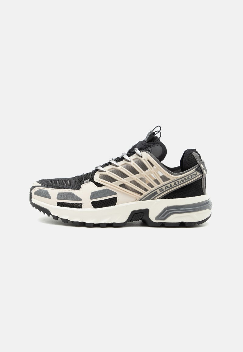 Chaussure de sport Salomon noire et beige avec tissu en mesh, embout renforcé, semelle coussinée et système Quicklace sur fond blanc.