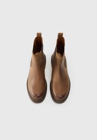 Bottes chelsea en cuir marron avec une texture lisse, des panneaux latéraux élastiques, des bouts ronds et des languettes pour un enfilage facile.