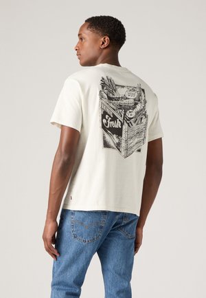 Camiseta de manga corta color crema con una ilustración gráfica de verduras y la palabra "Fresco" en la parte posterior; material de algodón suave.