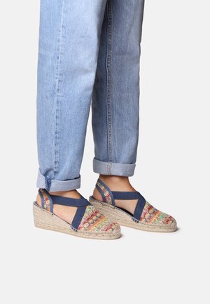 Wedge sandals with multicolored woven fabric upper, navy straps, and jute-wrapped sole. Casual design, suitable for warm weather.