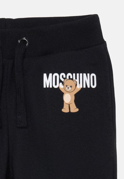 Svarta sweatpants med en ribbad midja, prydda med ett björngrafik och texten "MOSCHINO" i vitt. Materialet ser mjukt och elastiskt ut.