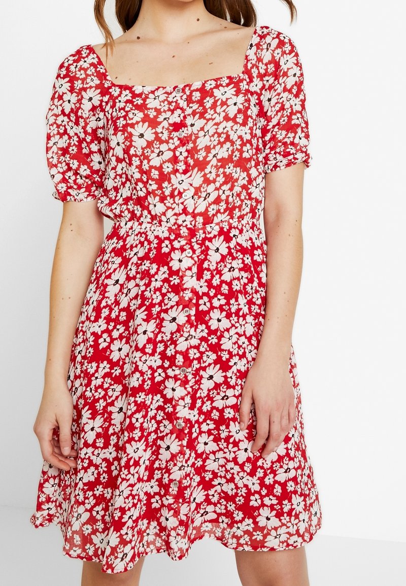 Rotes Blumenkleid mit kurzen, gepufften Ärmeln. Mit einem quadratischen Ausschnitt, einer durchgehenden Knopfleiste und einer taillierten Passform mit ausgestelltem Rock.