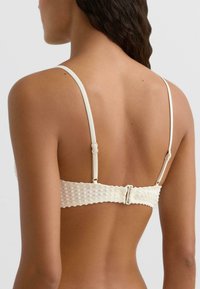 Fehér, texturált bralet vékony pántokkal. Hátsó részen ráncolt szalag és állítható kapcsos záródás jellemzi. Simogató, puha anyag, minimális díszítéssel.