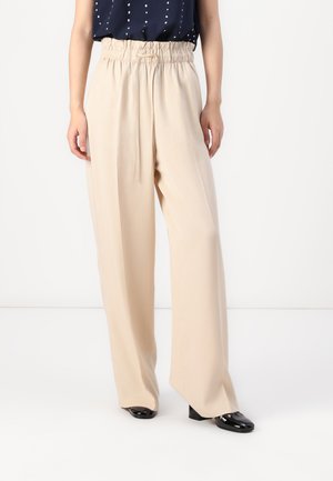 Beige wijde broek met een geplooide elastische tailleband, een gladde textuur en een cetera, gecombineerd met zwarte hoge hakken.